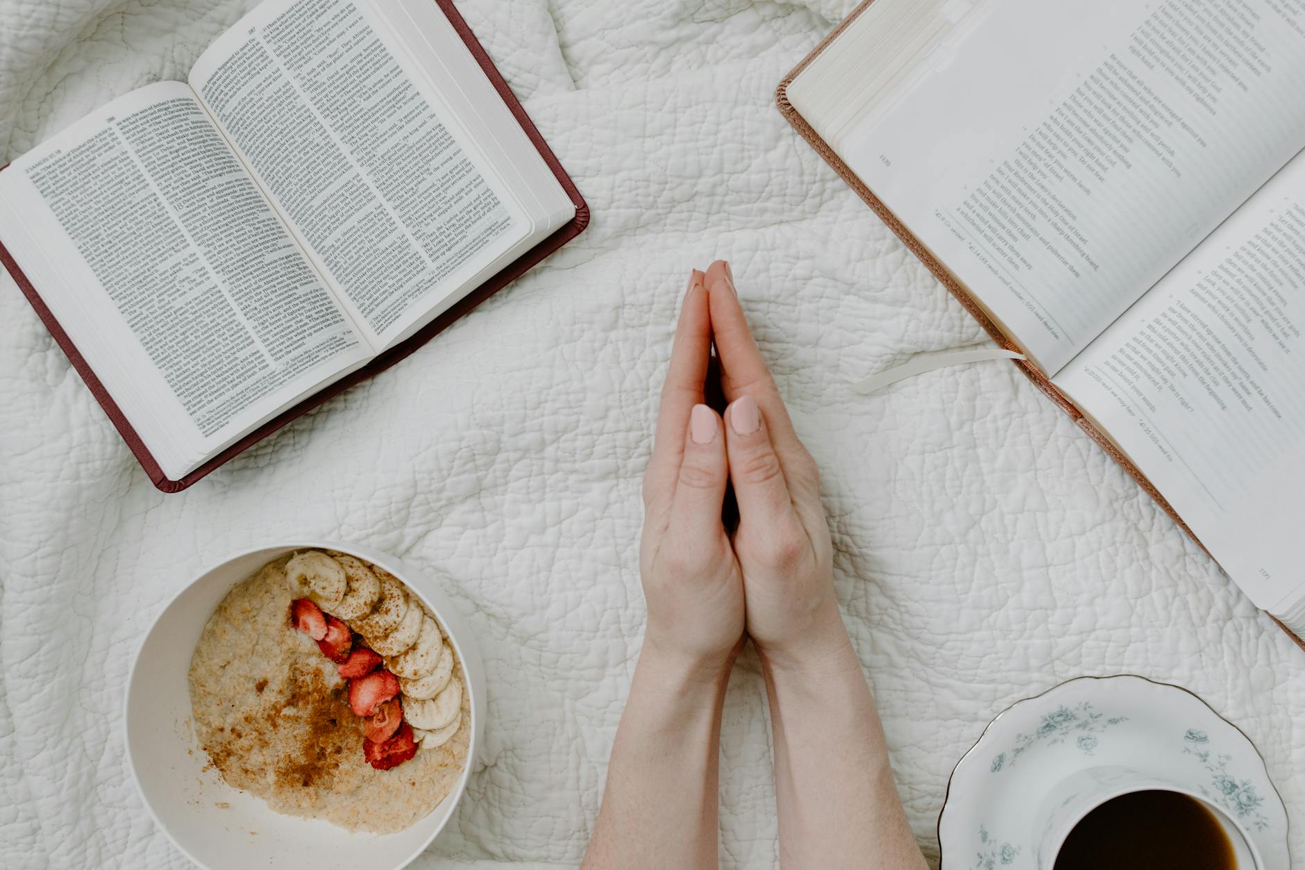 A serene morning scene with a person praying, an open Bible, oatmeal, and coffee.