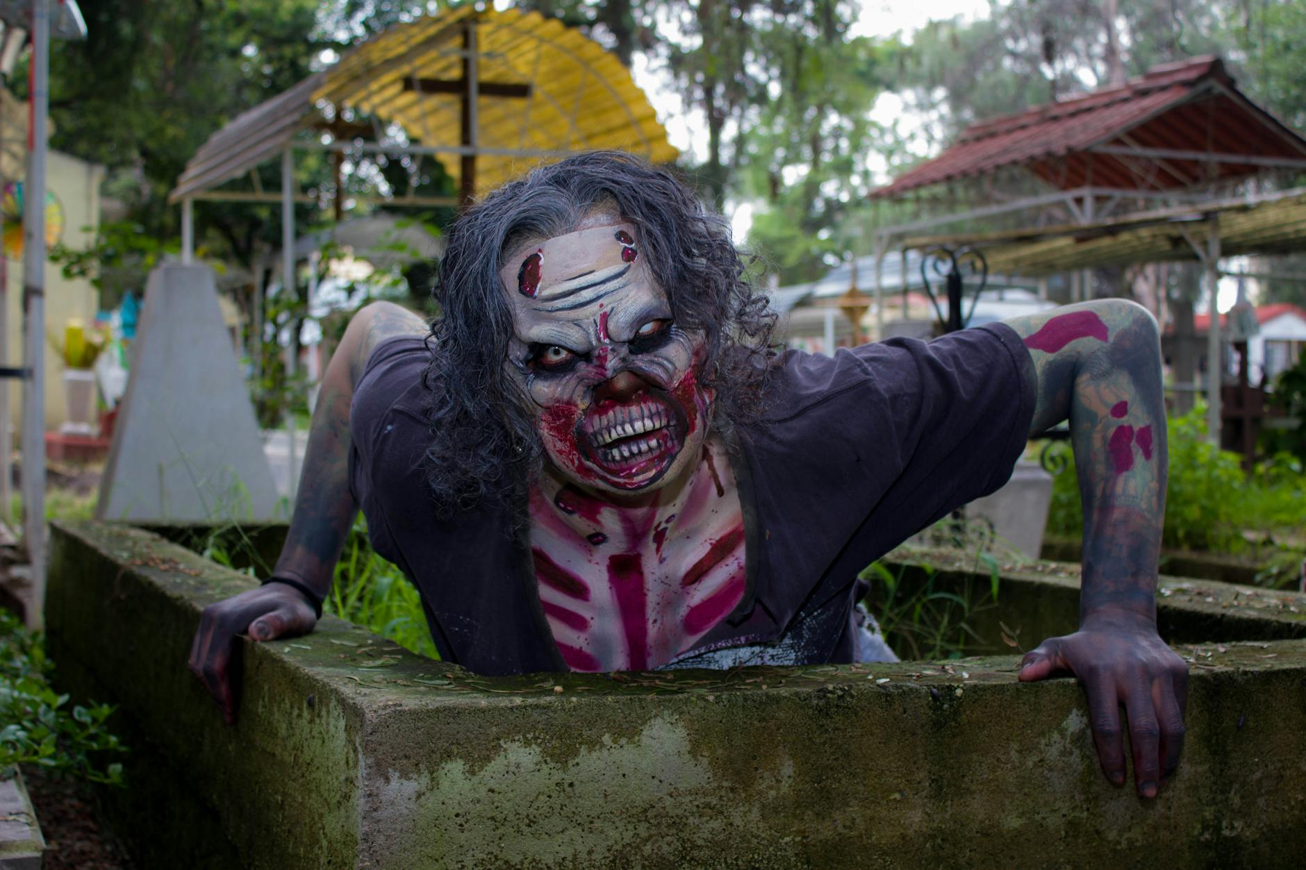 Frightening zombie character with detailed makeup in a cemetery setting, Ciudad de México.
