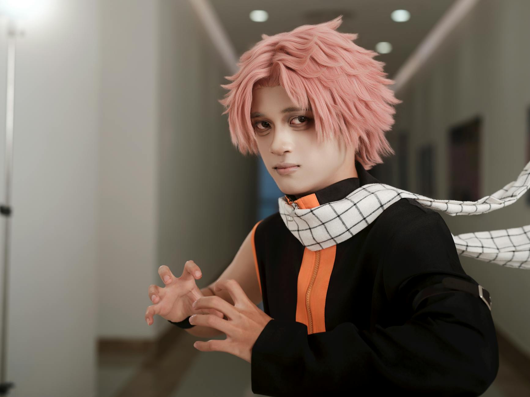 Young adult in anime cosplay costume with pink hair in a corridor.