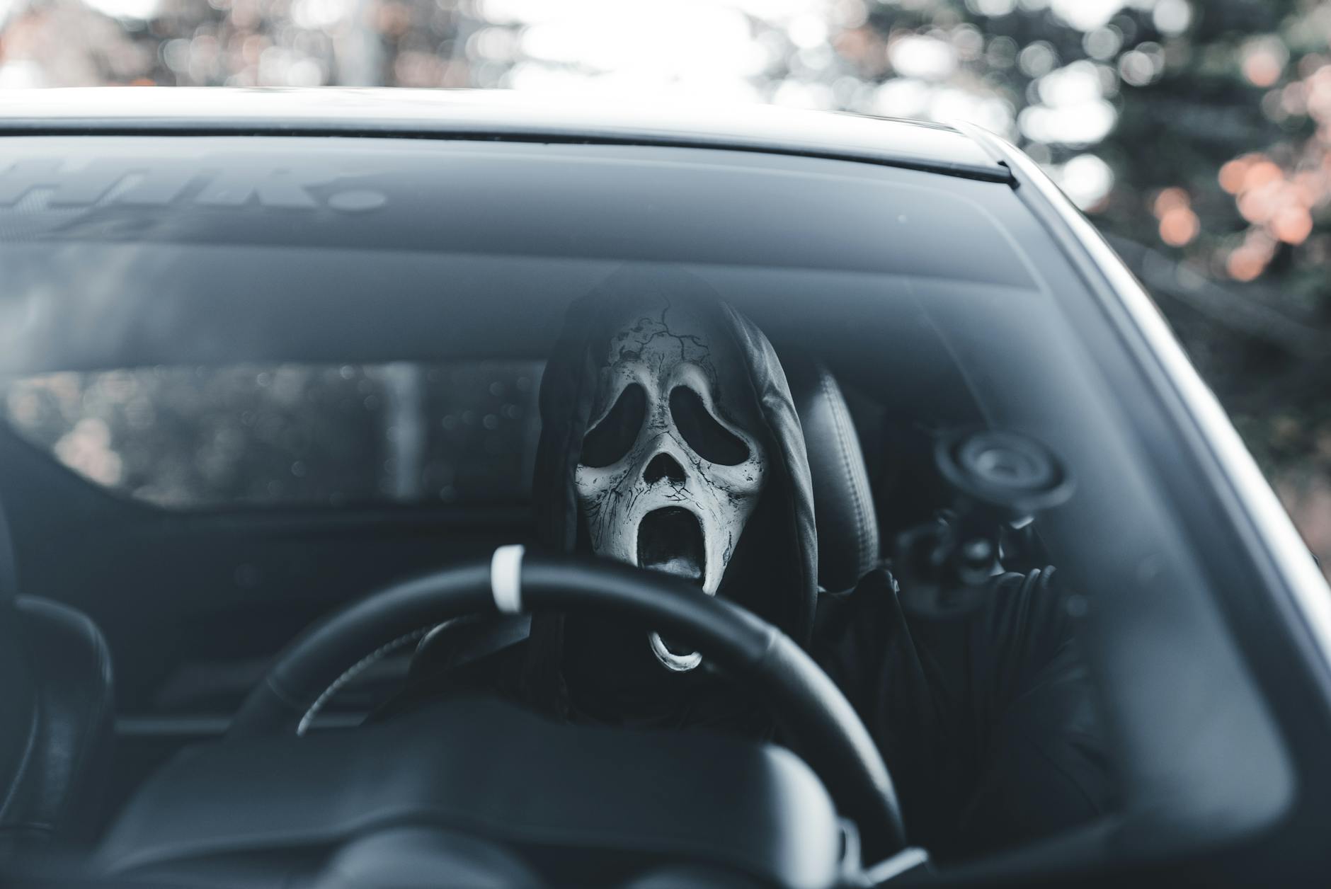 Masked individual in car adds an eerie vibe, suitable for Halloween themes.