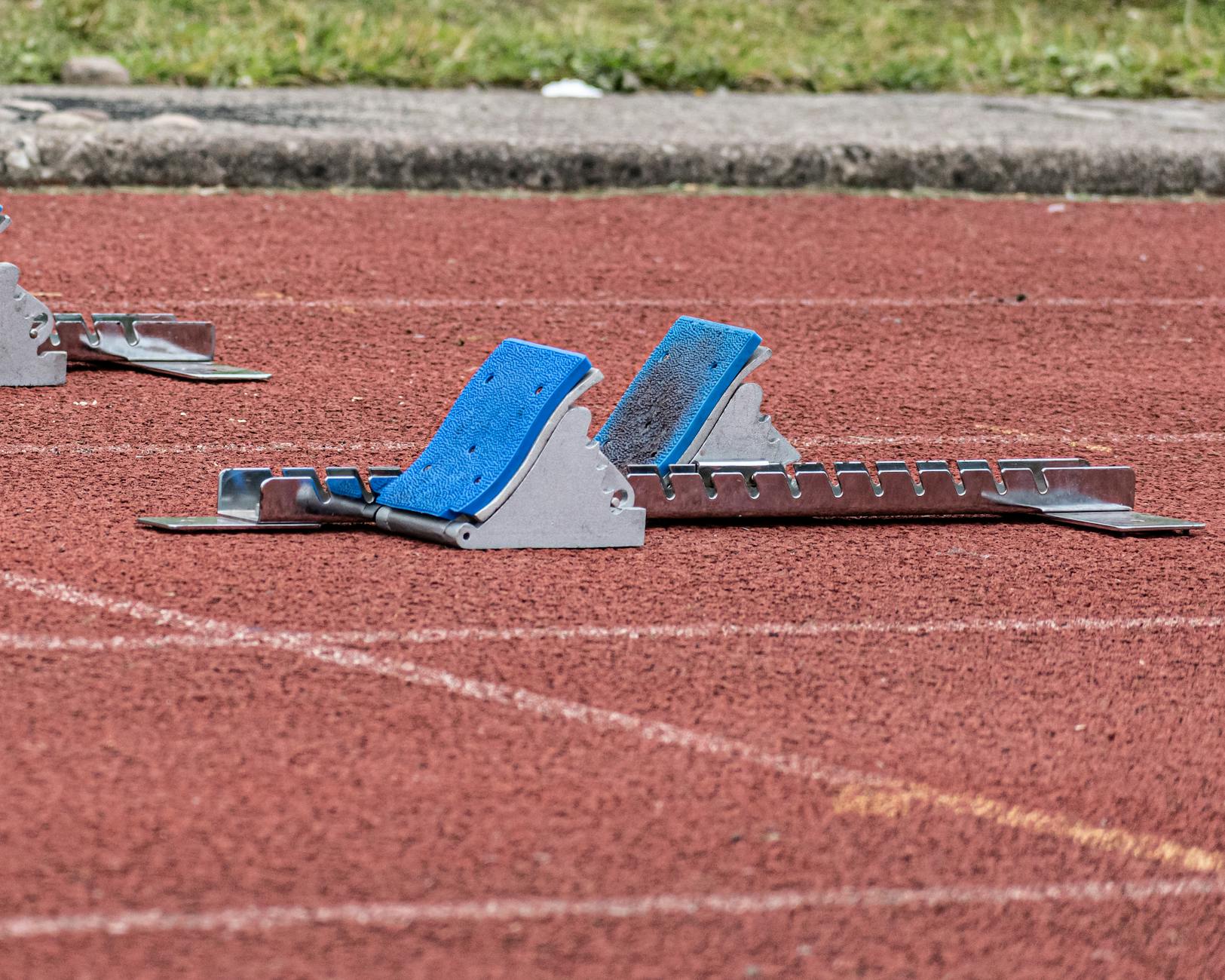 Close-up of starting blocks on a red athletics track, ready for a race.