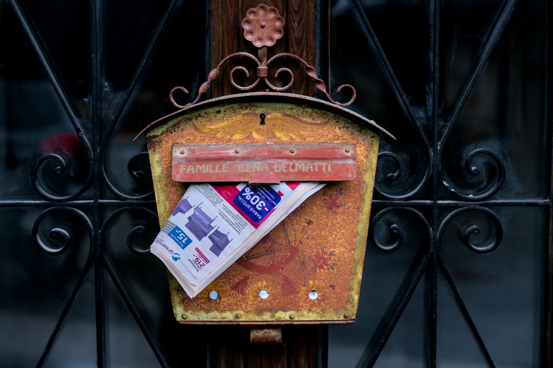Rustic rusted mailbox holding a newspaper in Saillon, Switzerland.