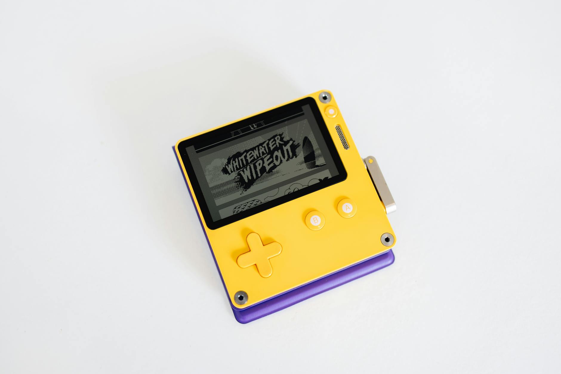 Close-up of a modern yellow handheld game console displaying 'Whitewater Wipeout' game.