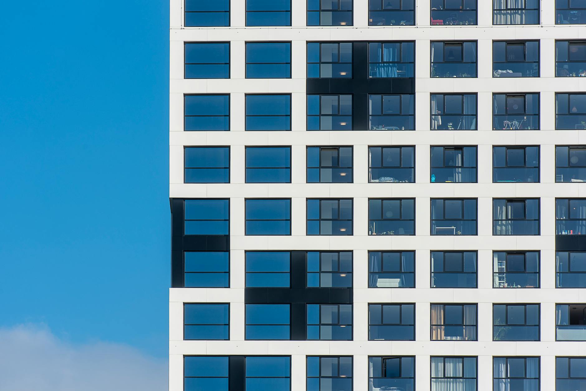 Close-up view of a modern building facade with grid windows against a clear blue sky.