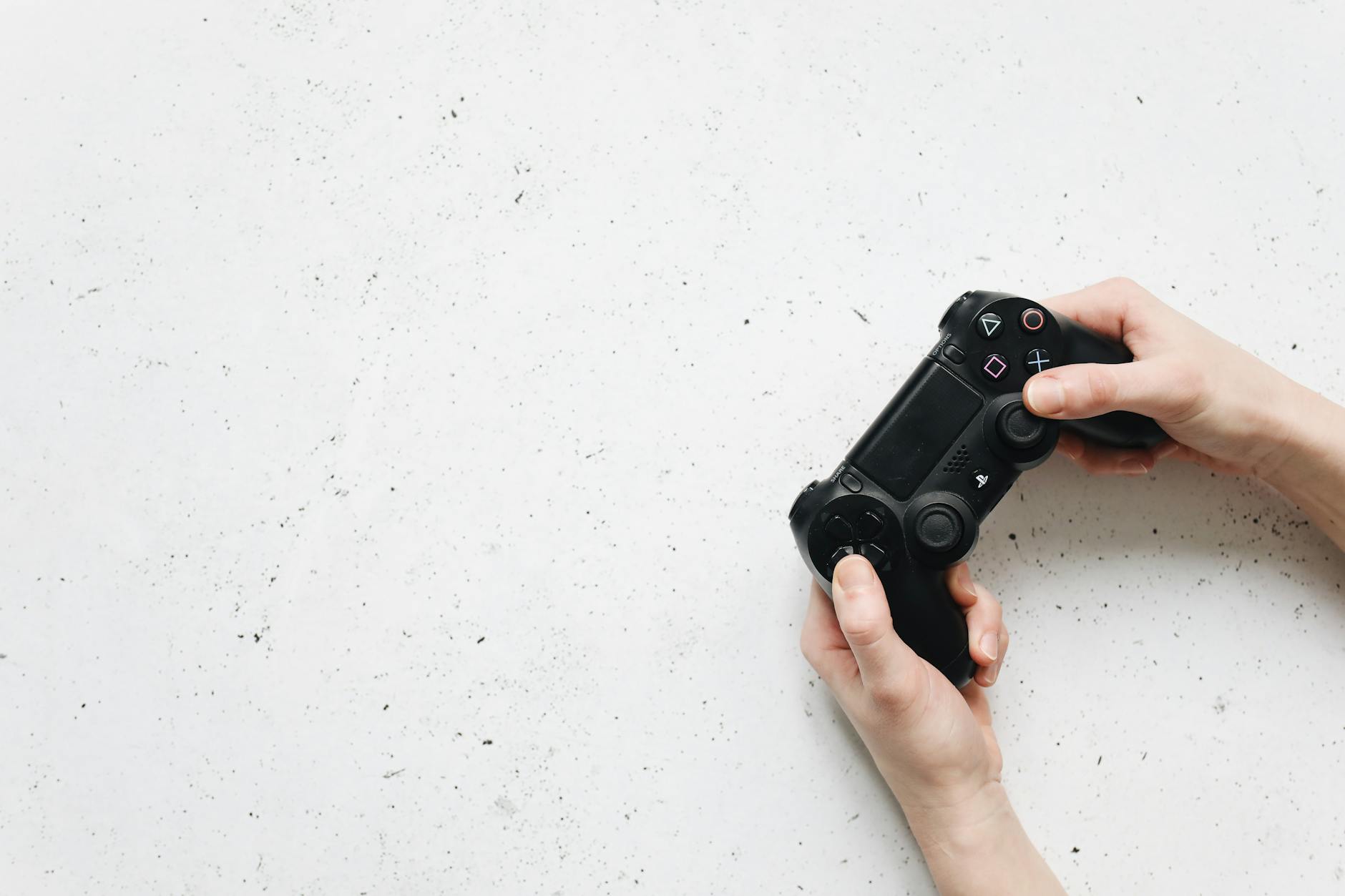 Close-up of hands holding a black game controller on a white background.