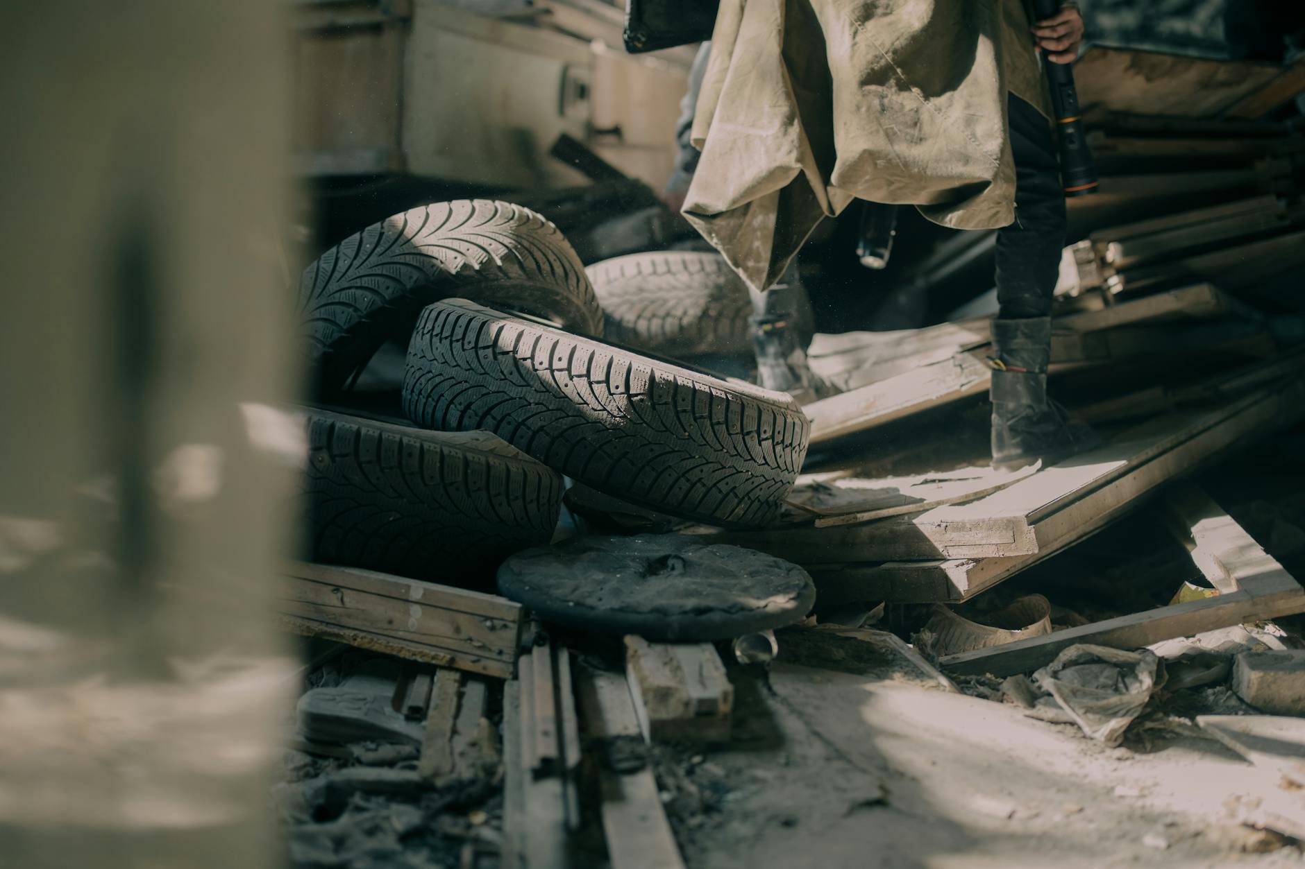 A gritty indoor shot of scattered tires and debris in an abandoned warehouse.