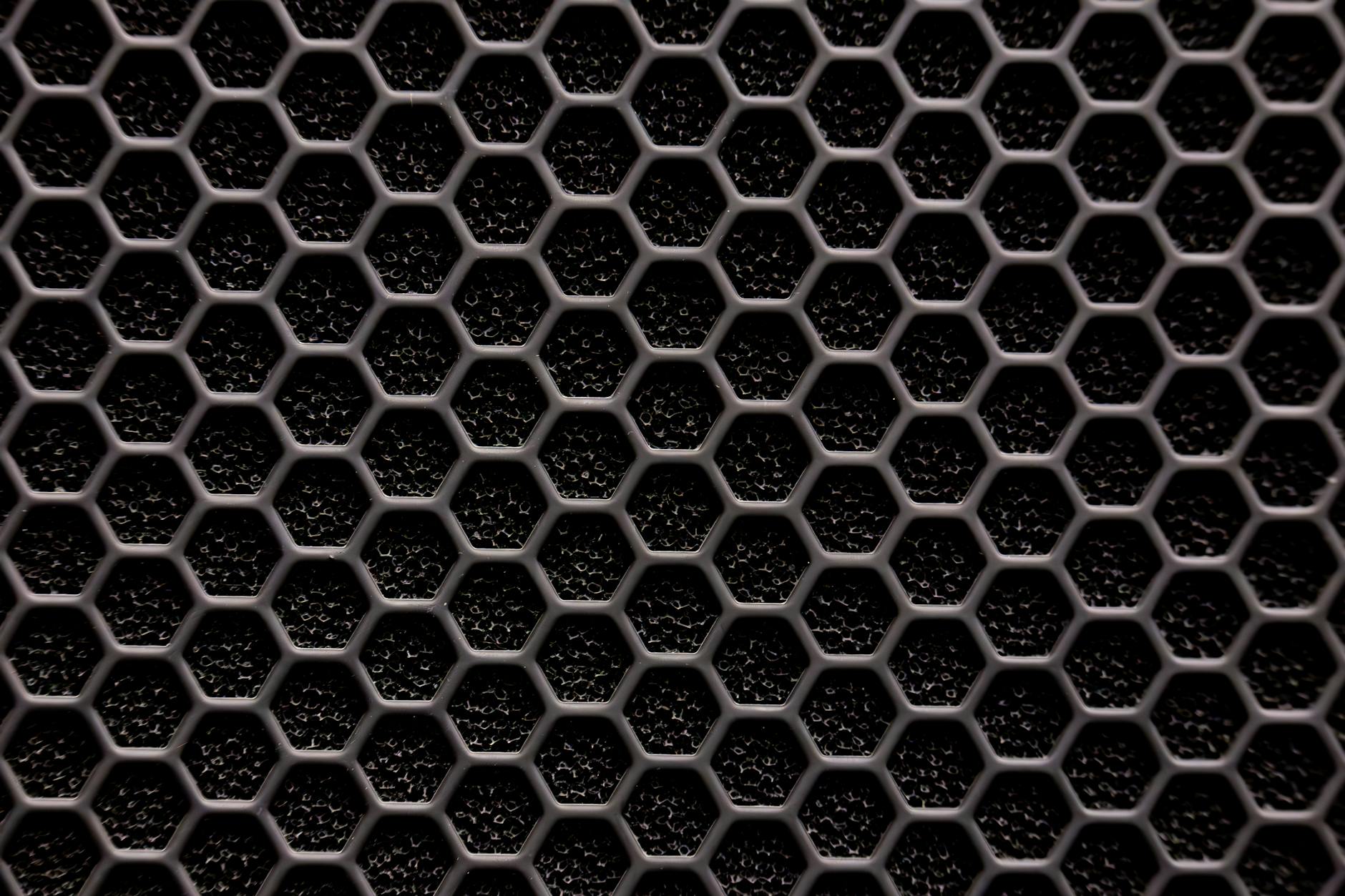 Close-up of a metallic hexagonal grid pattern, resembling a honeycomb structure.