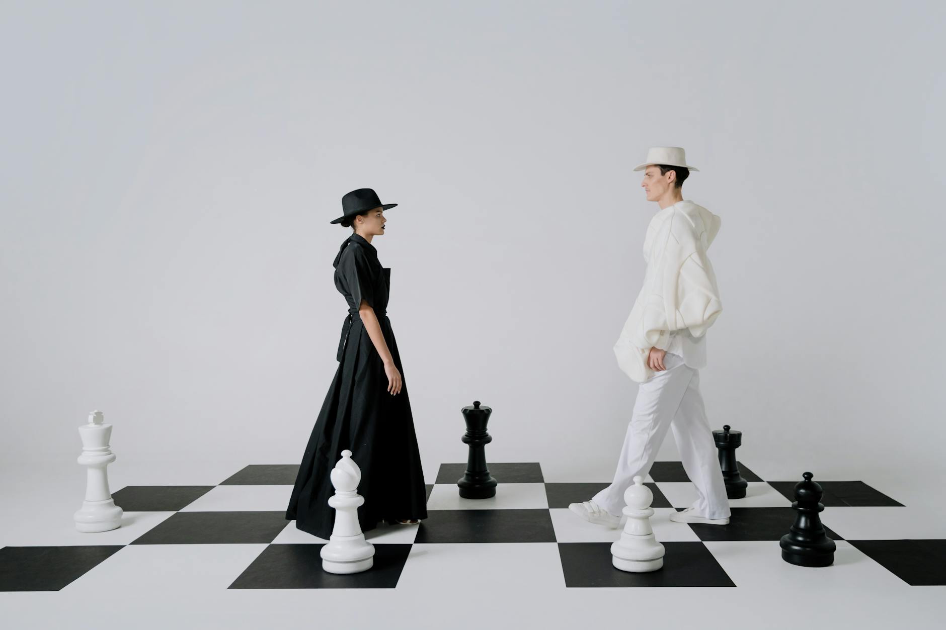Artistic portrayal of fashion on a chessboard with models embodying black and white pieces.
