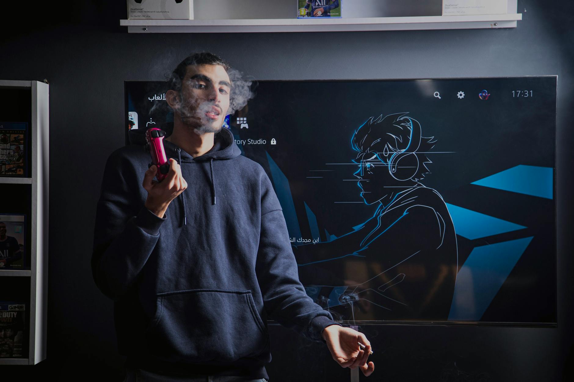 A young man in a hoodie vapes while standing in front of a gaming screen featuring an anime drawing.