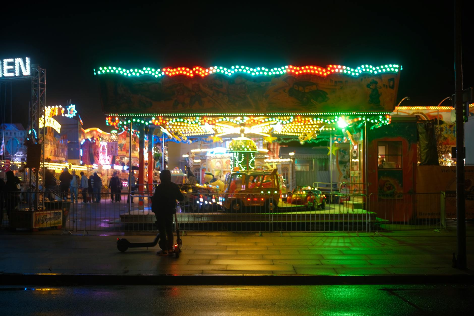 Colorful amusement park at night in Potsdam, Germany, showcasing lights and rides.