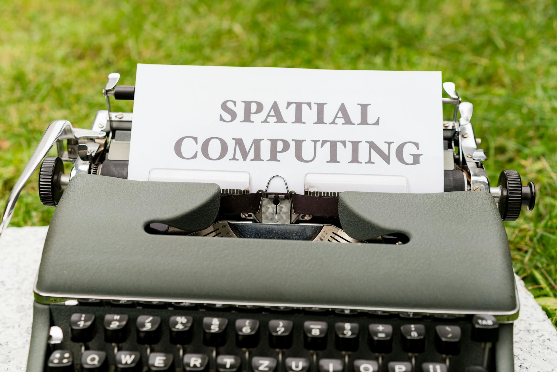 A vintage typewriter displays 'Spatial Computing' on paper in an outdoor setting.