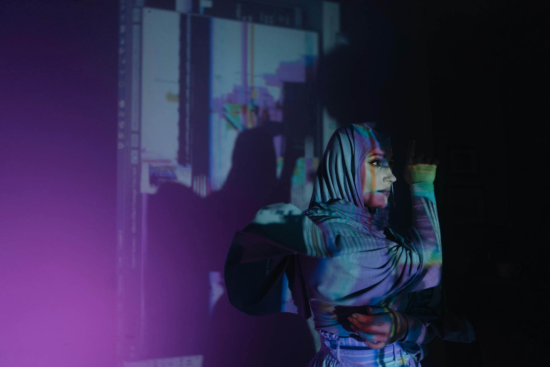 A vibrant portrait of a woman in hijab with artistic light projections and deep shadows.