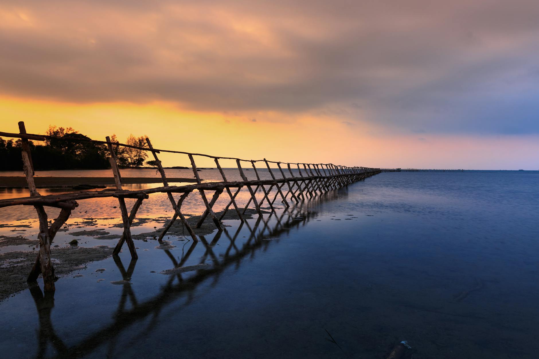 A tranquil sunset view of a wooden jetty over calm waters in Phu Quoc, Vietnam.