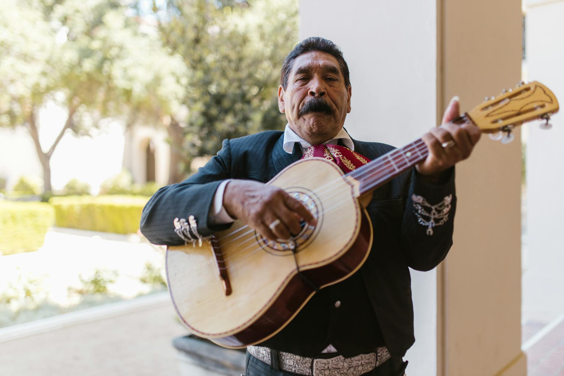 Mariachi musician playing guitar outdoors in traditional attire. Capturing cultural essence.