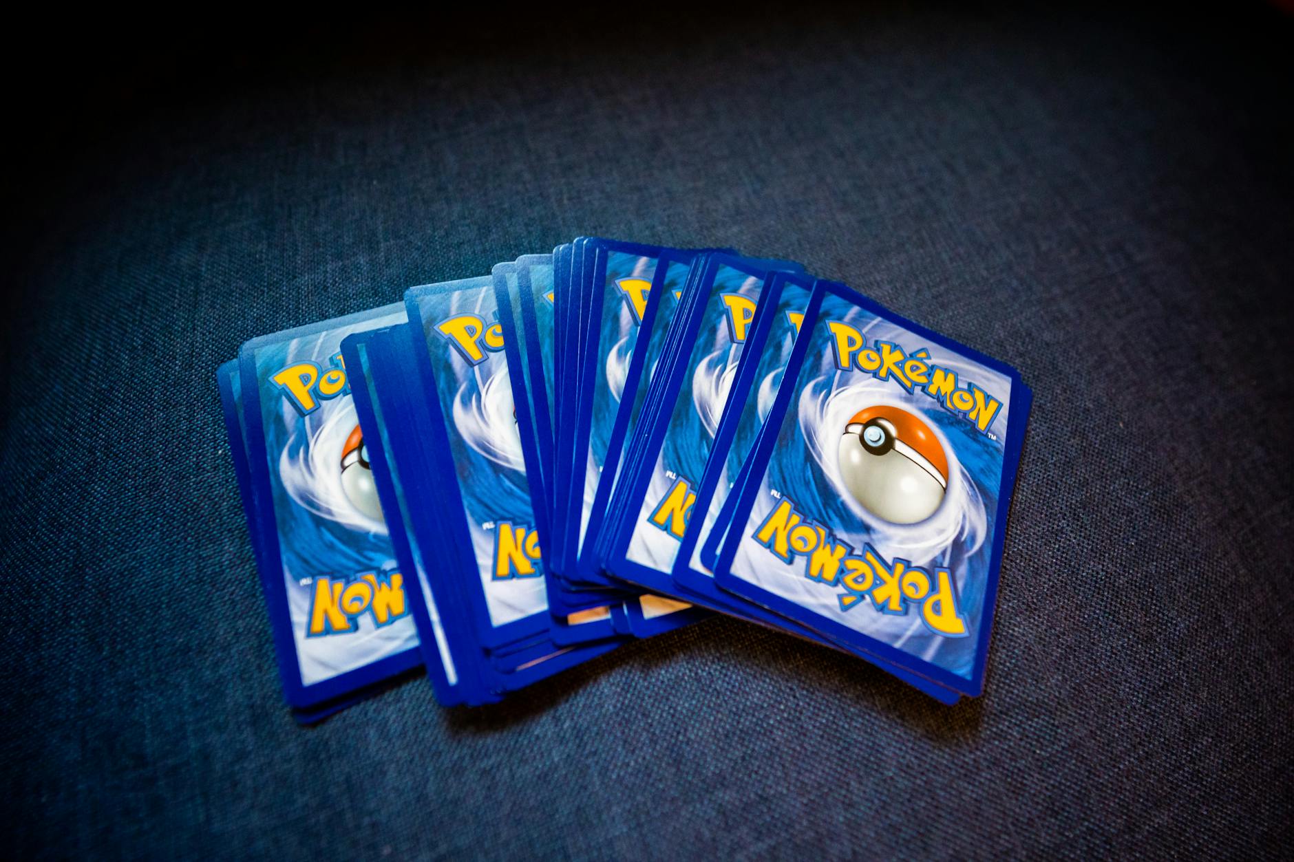 A collection of Pokemon trading cards laid out on a dark surface, showcasing their distinct back designs.