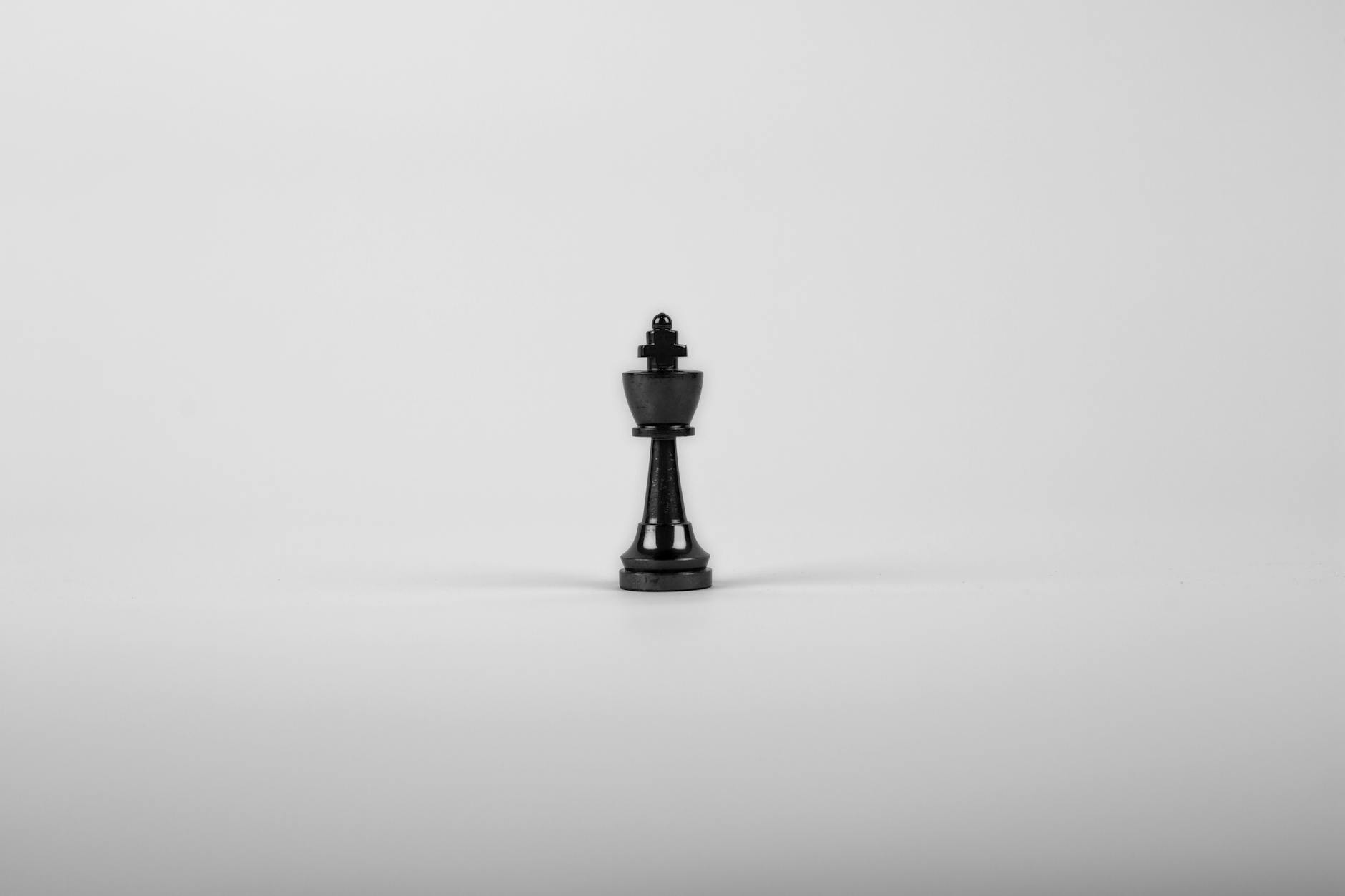 A minimalist black chess king piece on a white background, representing strategy and power.