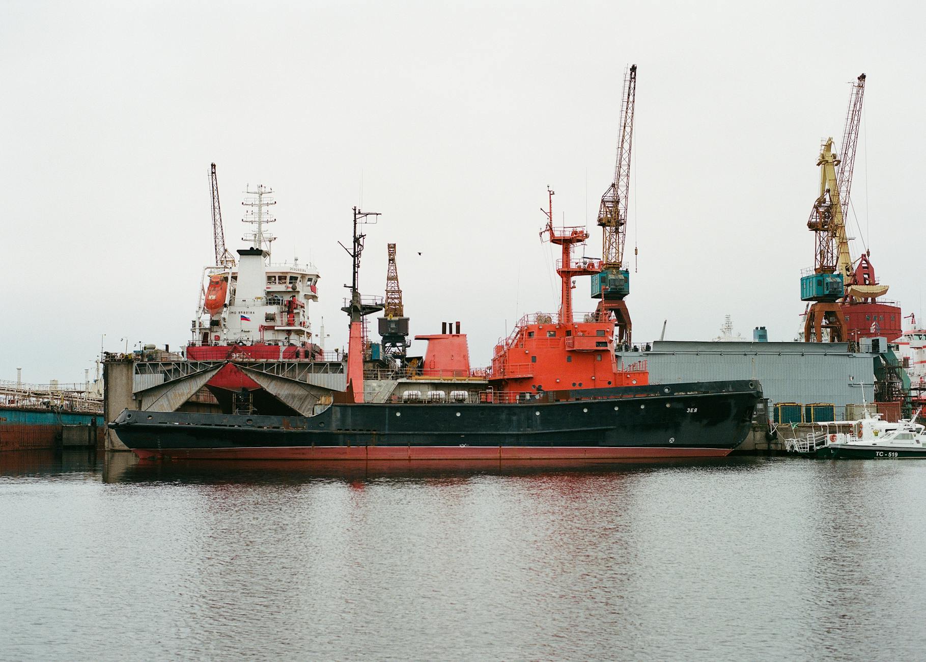 View of industrial cranes and ships docked at a port in Saint Petersburg, Russia. No people visible.