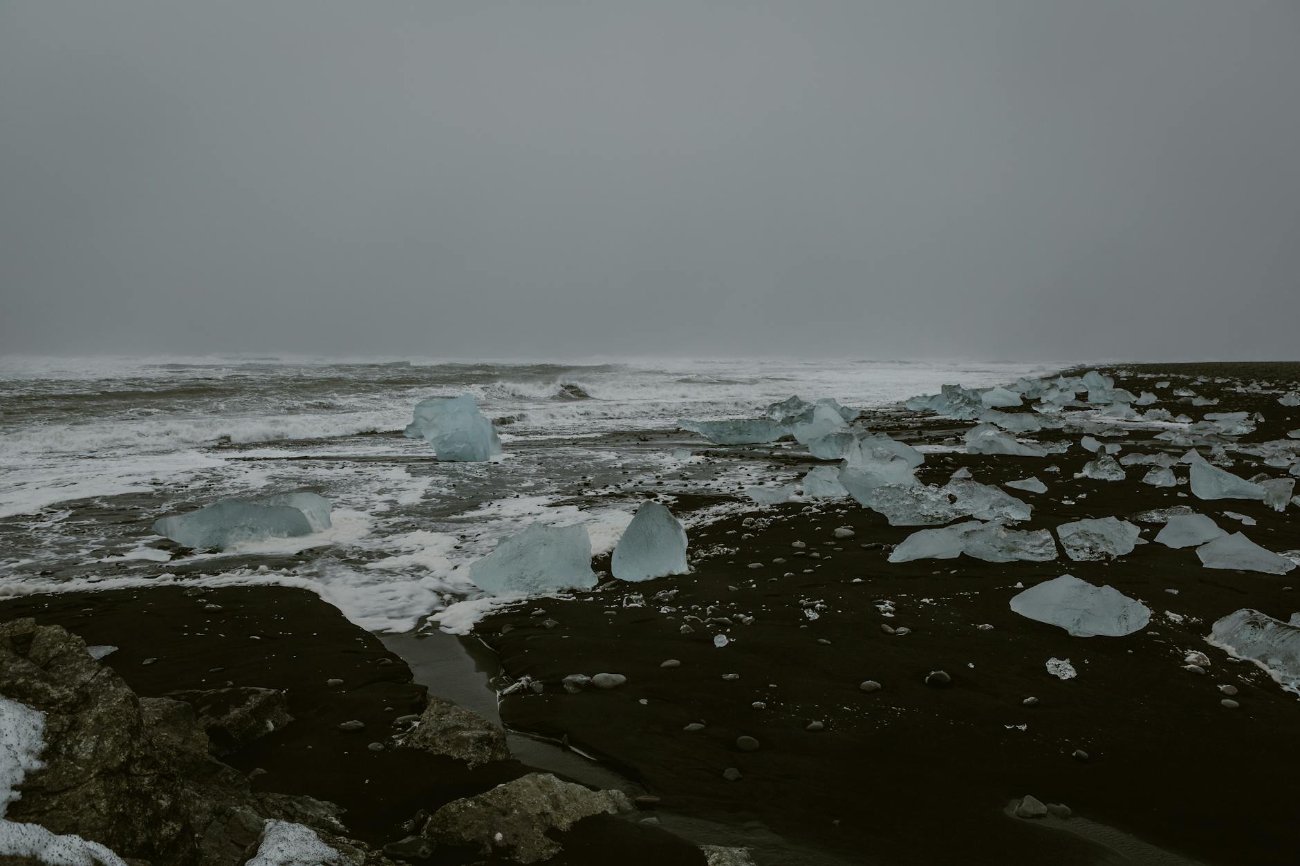 Icelandic beach with ice chunks and black volcanic sand creates a dramatic landscape.