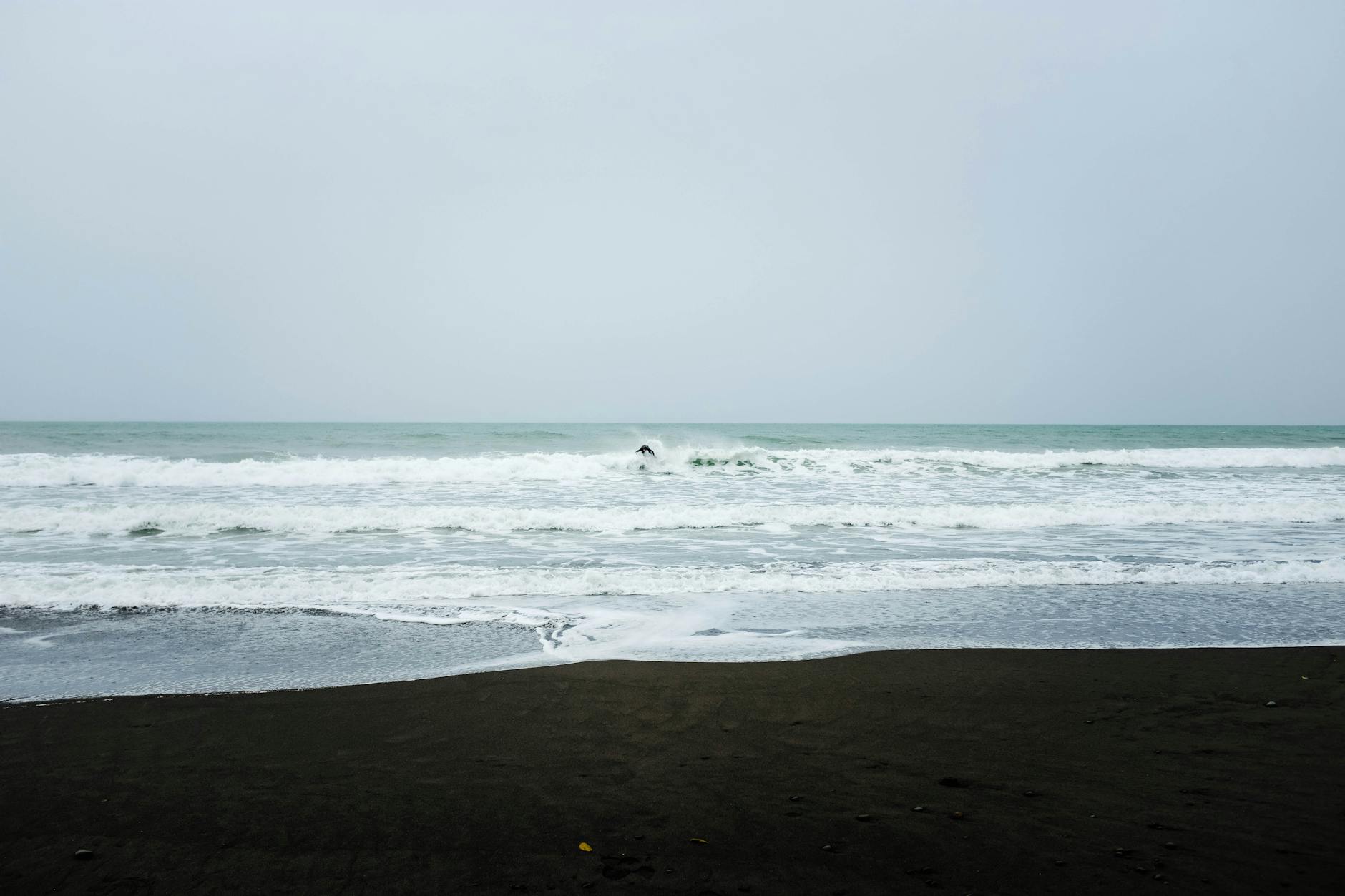 A tranquil beach with gentle waves and overcast sky creating a peaceful coastal scene.