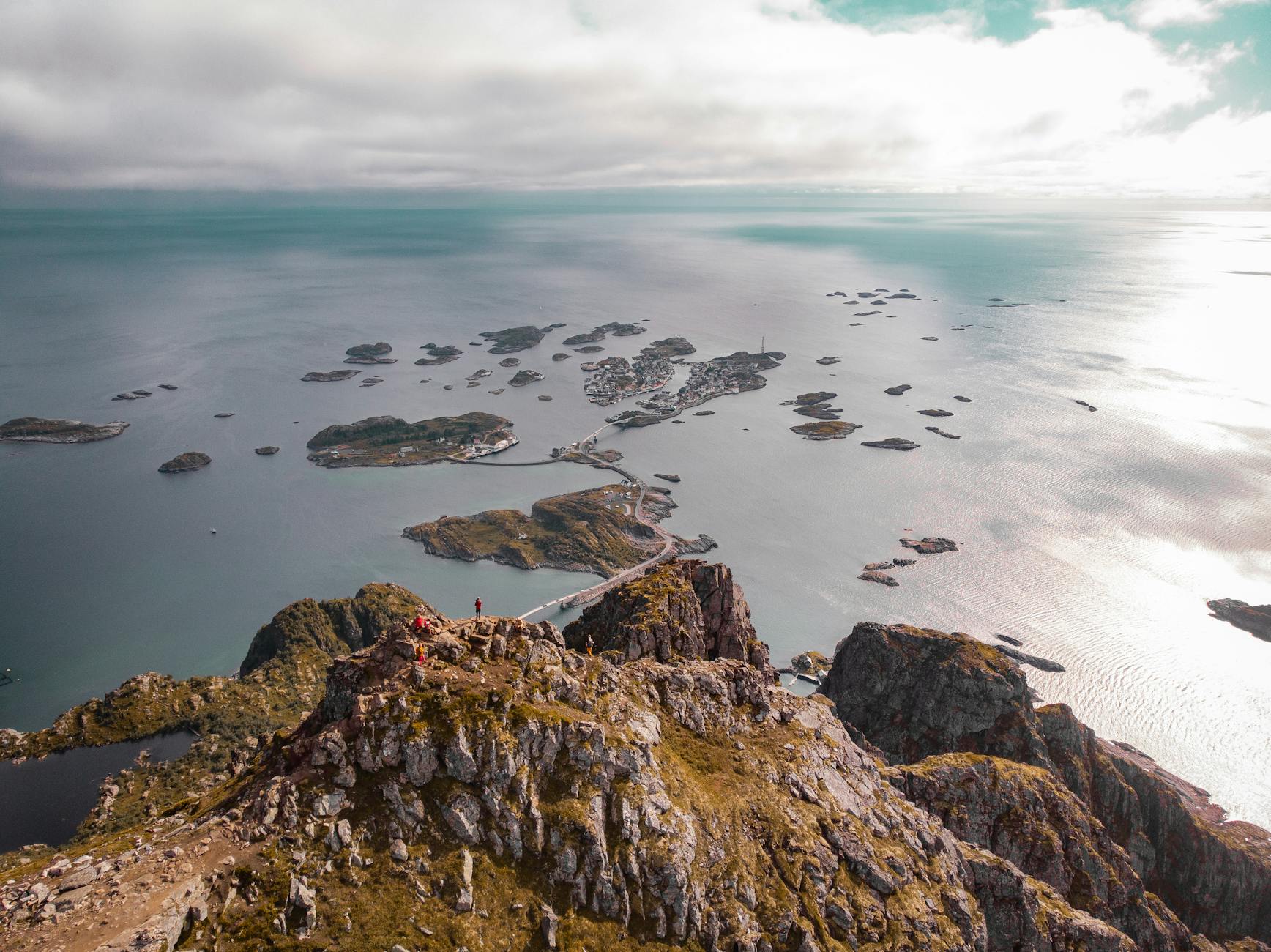 Stunning aerial view of Henningsvær's scenic islands, rocky terrain, and ocean during day.