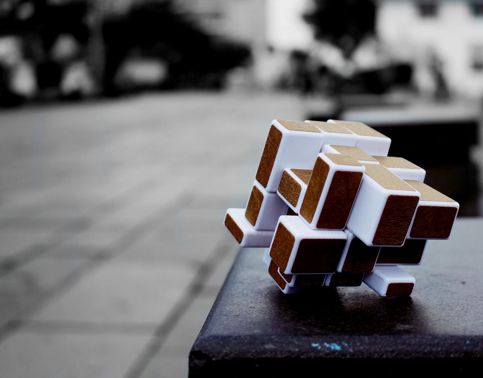 Artistic cube puzzle placed on a surface in an urban setting, capturing depth and focus.