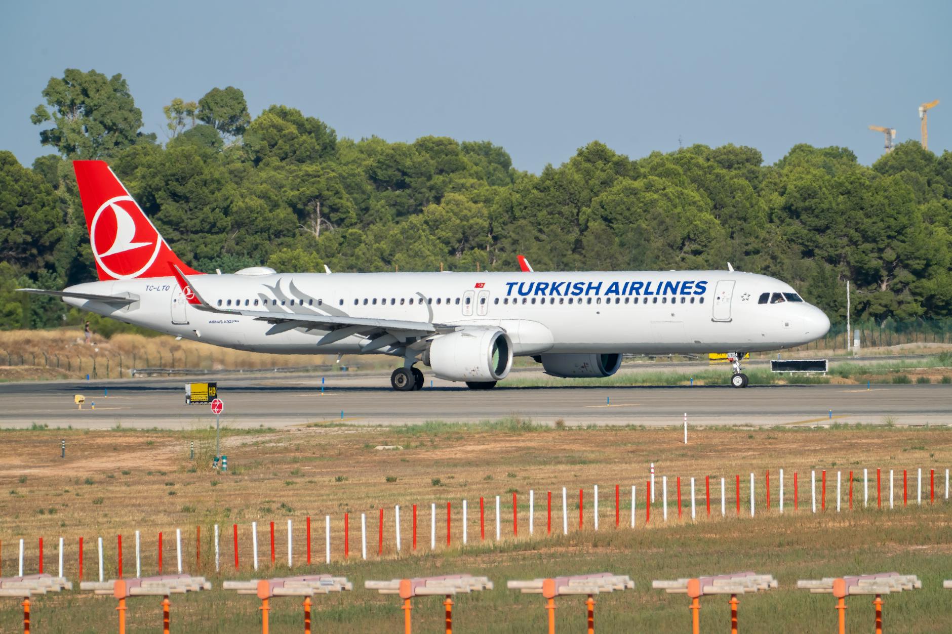 Turkish Airlines Airbus A321neo taxiing at Manises Airport on a sunny day.