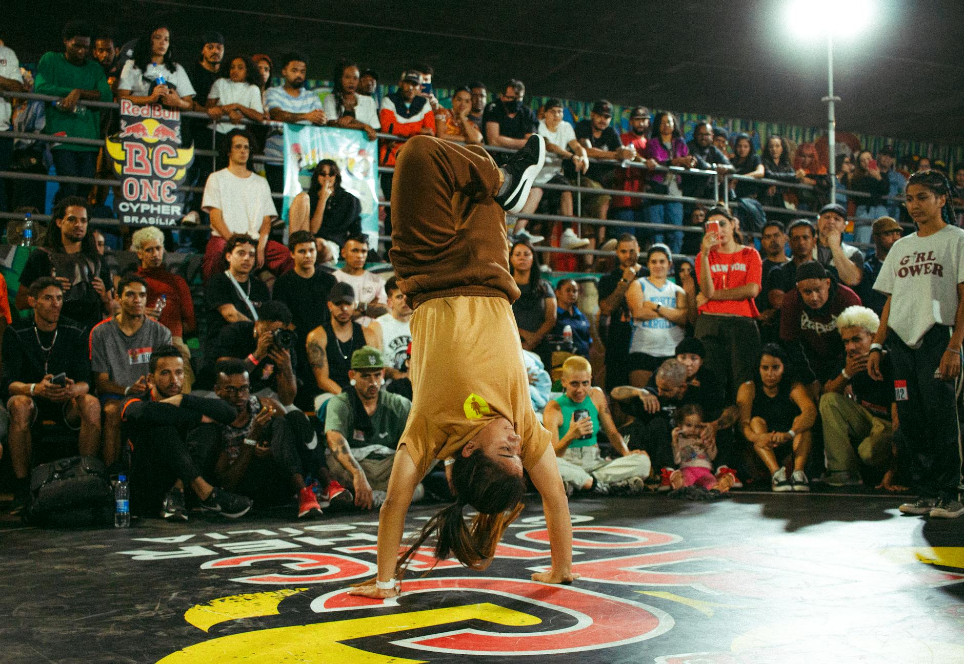 A dynamic breakdancer impresses a large audience with agility and balance.