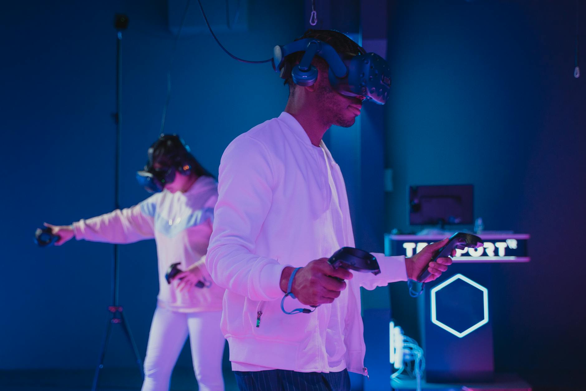 Two adults engaged in a virtual reality gaming session wearing VR headsets and controllers.