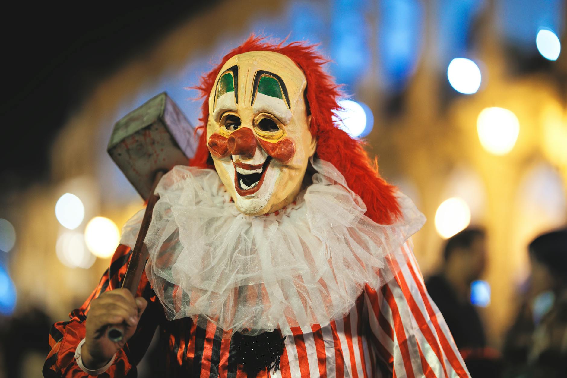 A clown in a vibrant costume participates in the Arequipa Halloween parade at night.