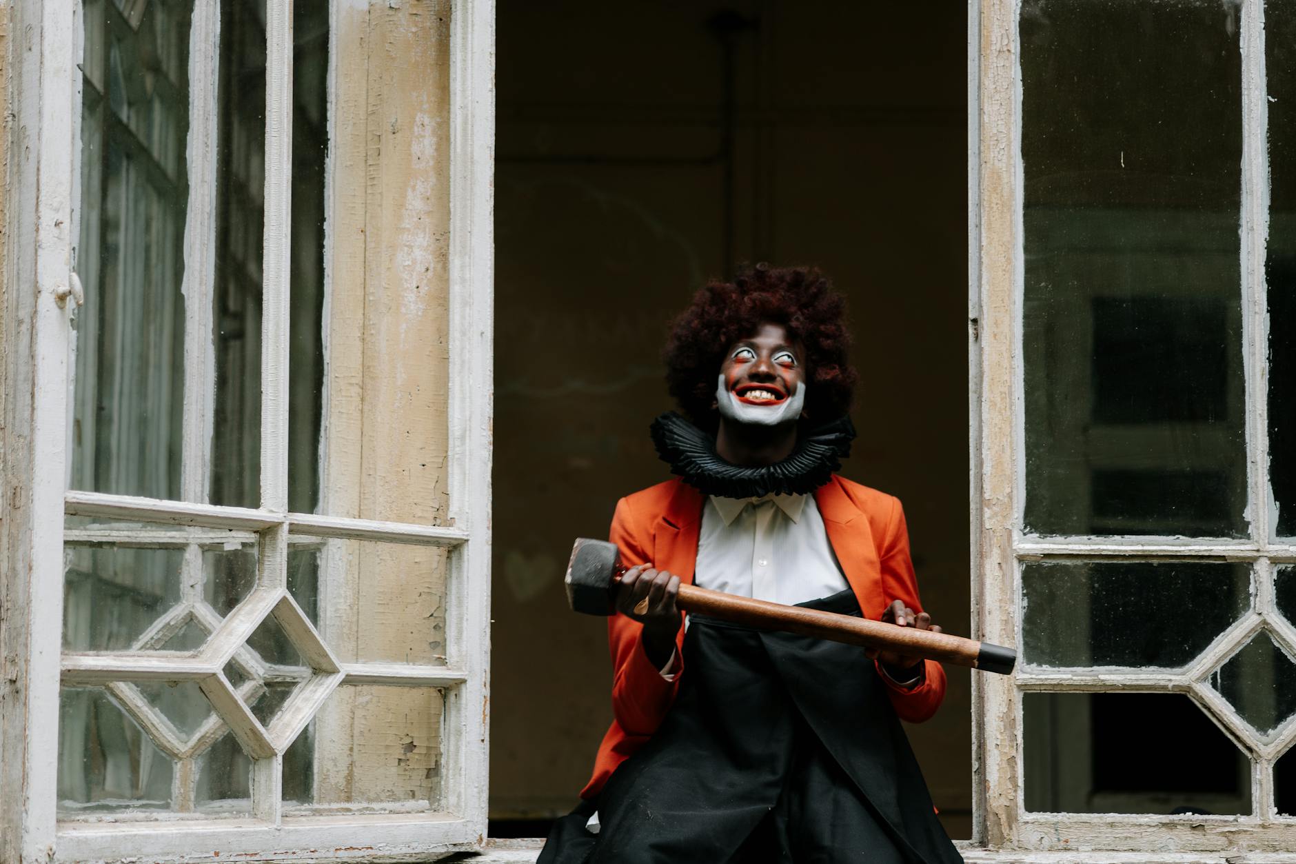 A frightening clown with a sledgehammer in an old, eerie building. Perfect for horror themes.
