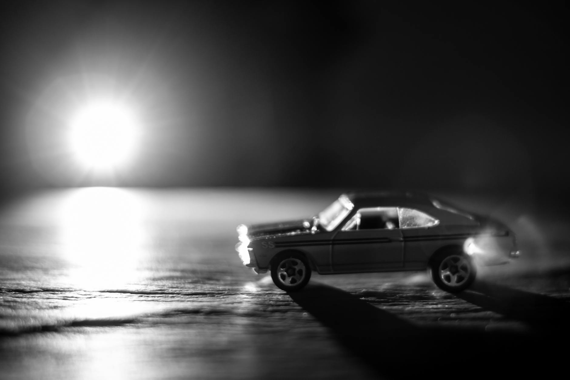 A dramatic black and white photo featuring a toy car with bright light creating a striking contrast.