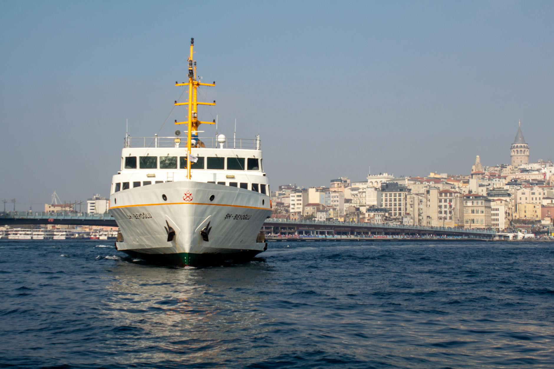A ferry crossing the Bosporus with Galata Tower in the background on a clear day in Istanbul, Turkey.