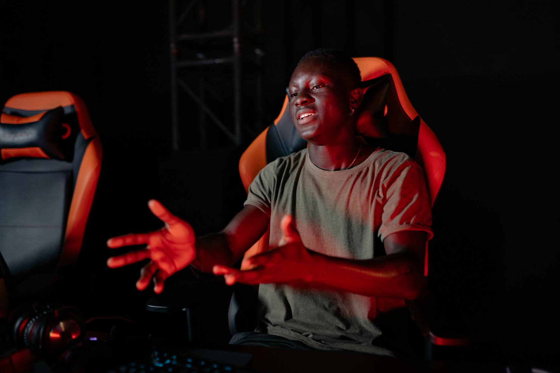 A young man passionately reacting while sitting in a gaming chair indoors.