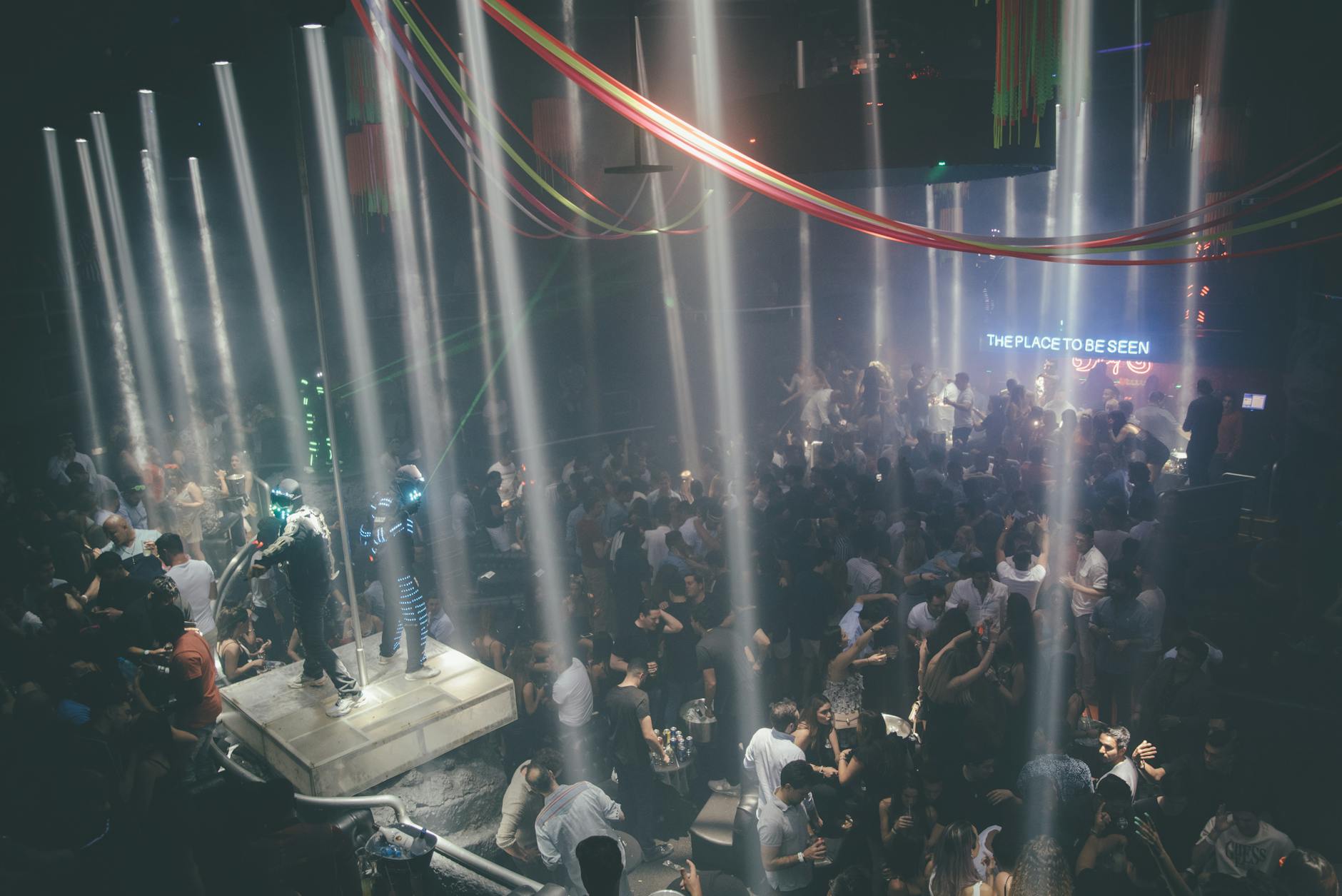 Energetic nightclub scene with people dancing under dramatic lighting and enjoying the vibrant atmosphere.