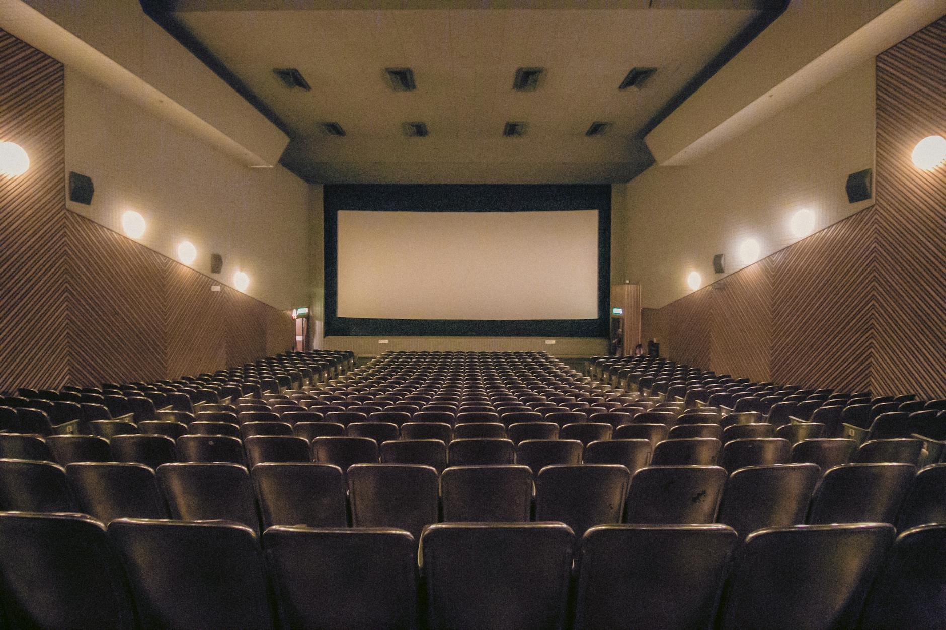 A vacant theater showing rows of seats and a large screen.