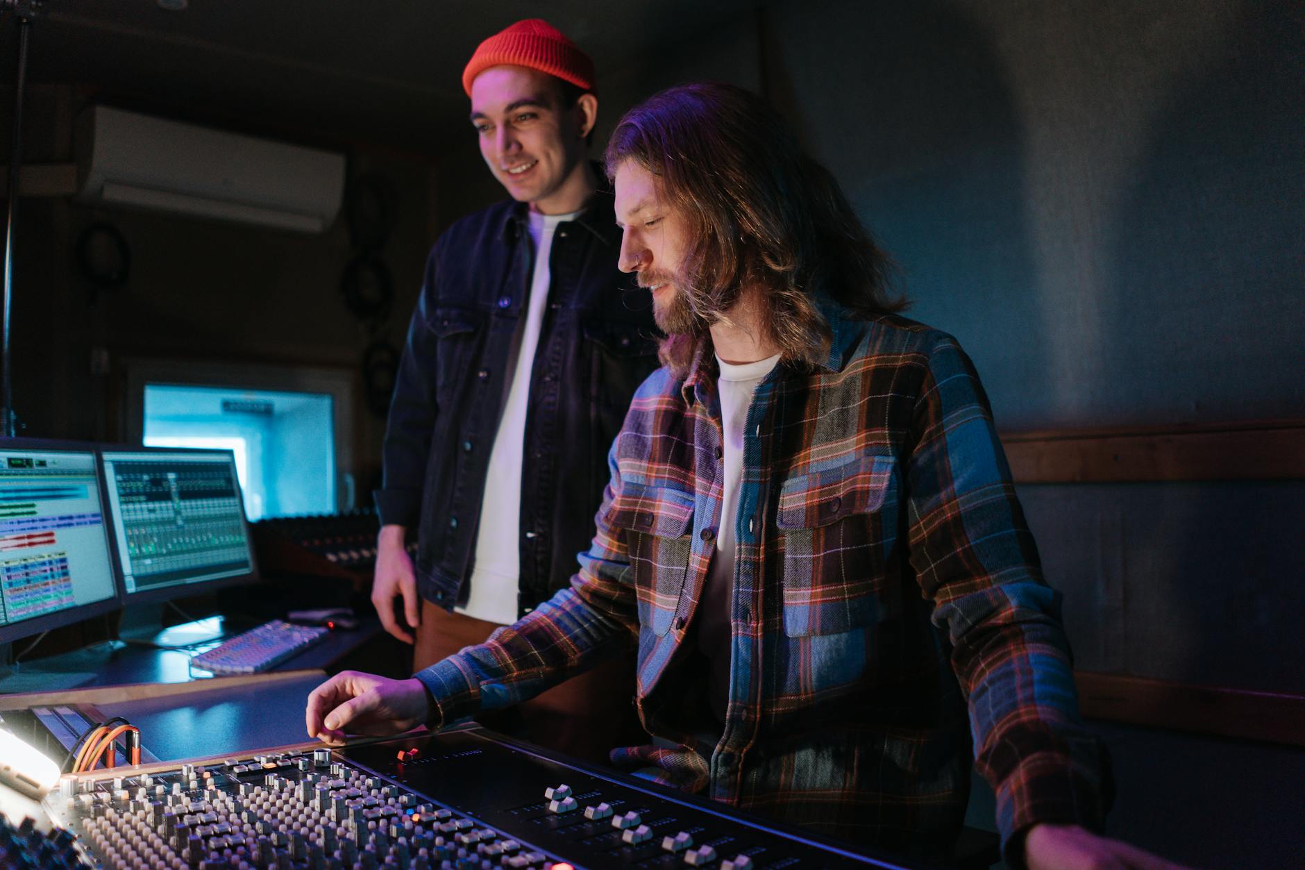 Two sound engineers collaborate at a mixing console in a professional music studio.