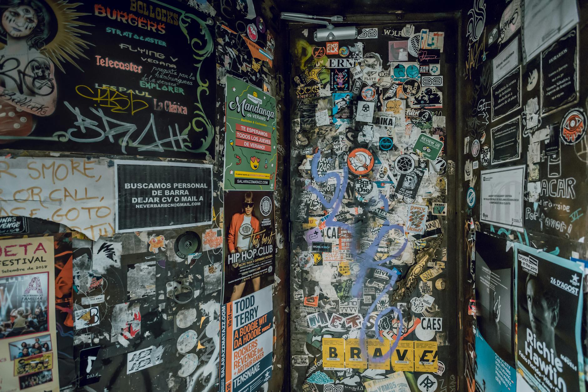 Eye-catching wall covered with graffiti, stickers, and posters in a Barcelona alleyway.
