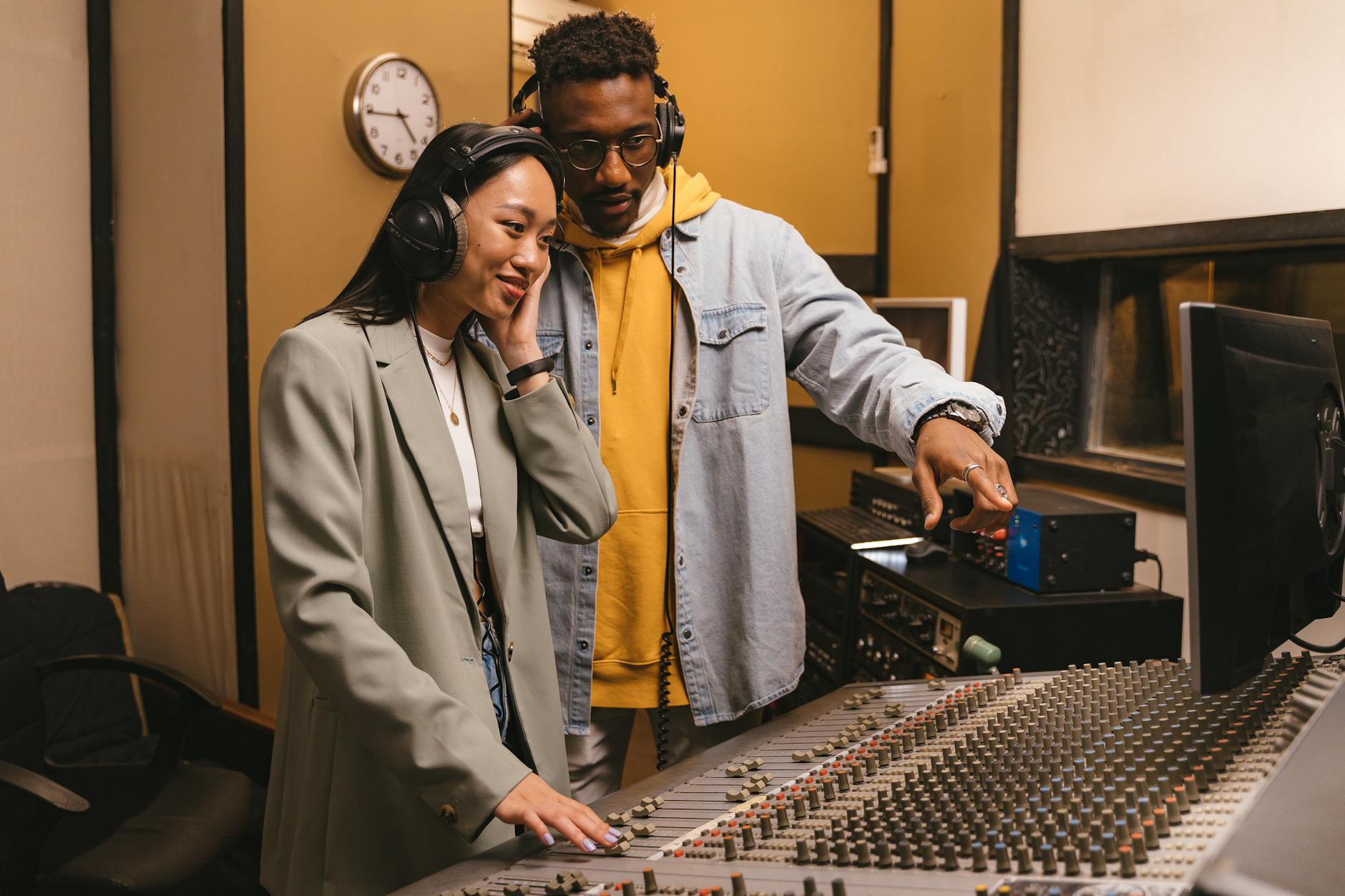 Two musicians collaborating in a professional recording studio with audio equipment.